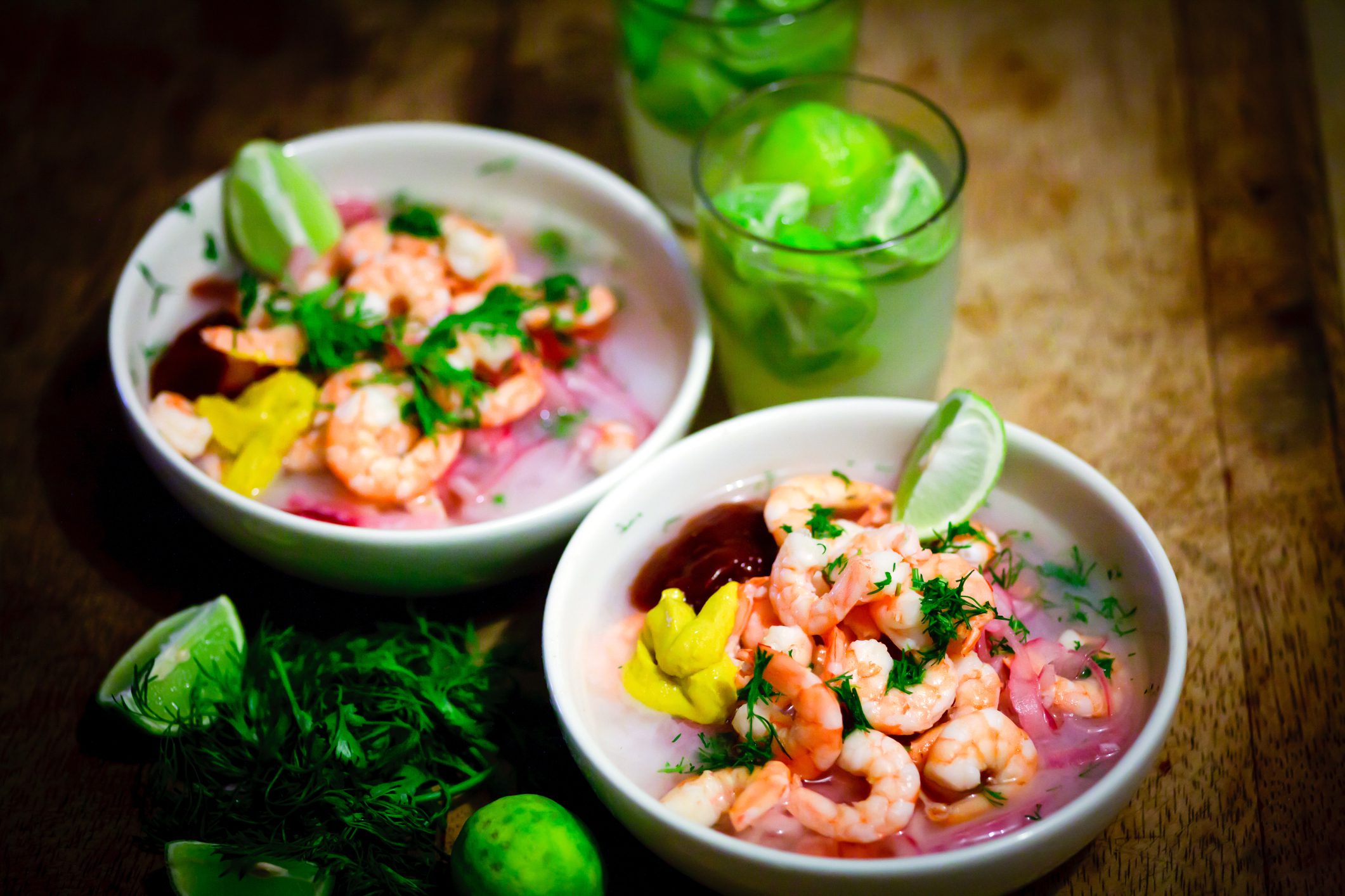 Two bowls of shrimp ceviche with wedges of lime